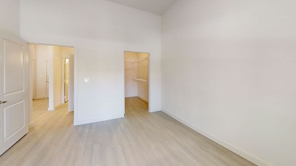 A white room with a wooden floor and a door on the left.