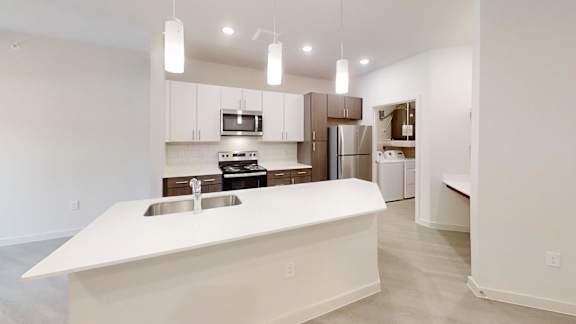 Modern kitchen with twotone cabinetry and island sink at Cantarra Apartments, Texas