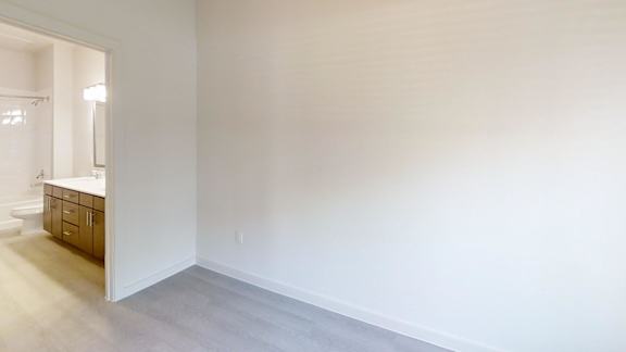 A large empty room with a white wall and a wooden floor.