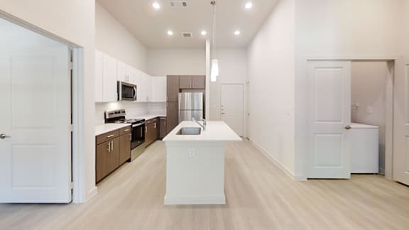 Open concept kitchen with island and vaulted ceiling at Cantarra Apartments, Manor, TX