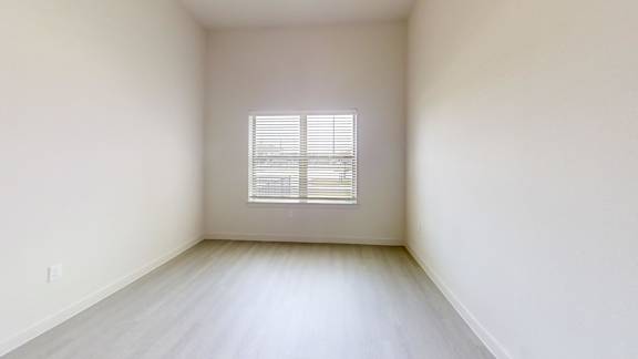 A room with a window covered by white blinds.