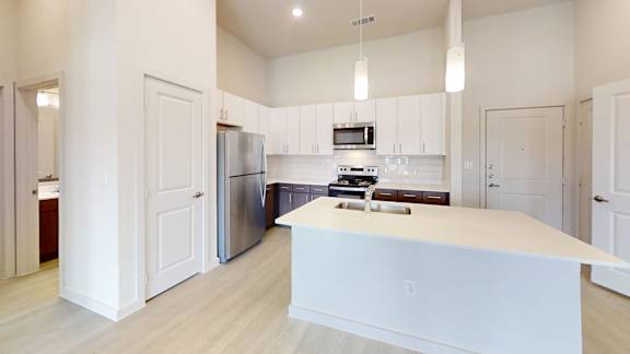 A kitchen with white cabinets and a white island.