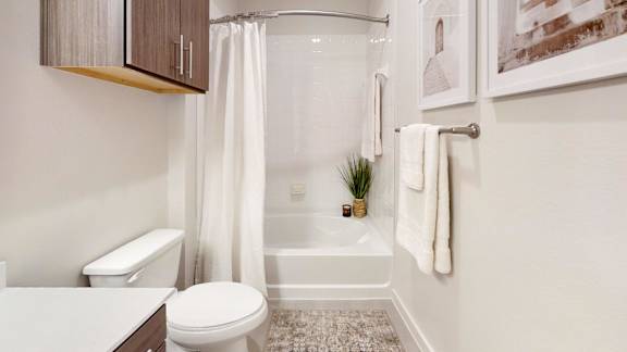 A white toilet sits next to a white bathtub in a bathroom.