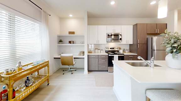 A modern kitchen with a white countertop and a wooden rolling cart.