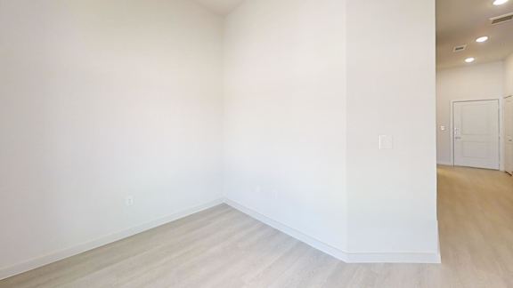Empty room with light wood flooring and white walls at Cantarra Apartments, Manor, Texas