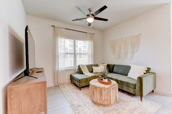 Living room with green sectional sofa and ceiling fan 2 at Cantarra Apartments, Manor, 78653
