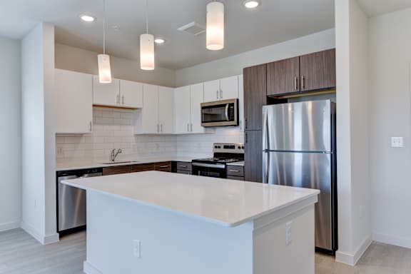 Modern kitchen with white island and stainless steel appliances at Cantarra Apartments, Manor, TX 78653