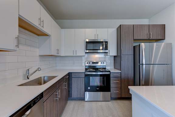 Two tone kitchen with white subway tile backsplash at Cantarra Apartments, Manor, TX