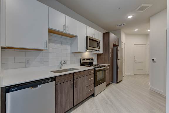 Galley kitchen with two tone cabinetry and stainless appliances at Cantarra Apartments, Manor, TX