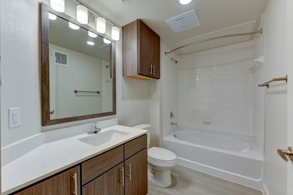 Full bathroom with tub shower combo and wood vanity at Cantarra Apartments, Manor