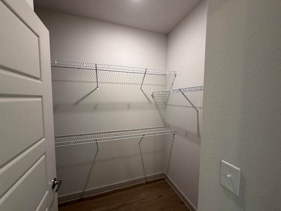 A white closet with a door and shelves.