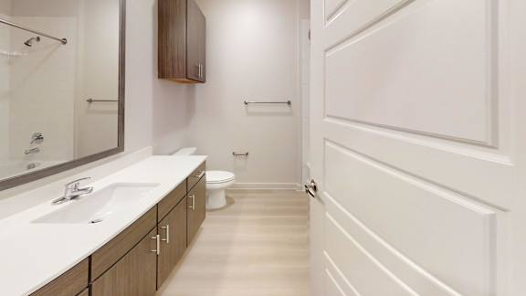 A white bathroom with a sink, mirror, and toilet.
