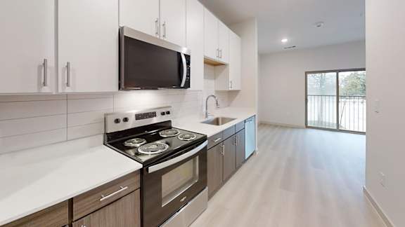A modern kitchen with a stove, microwave, and cabinets. at Bridge at Saffron Apartments, Austin, 78717