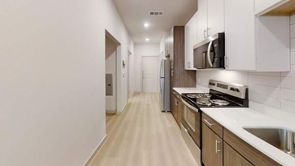 A kitchen with white cabinets and a stove top oven. at Bridge at Saffron Apartments, Austin, Texas