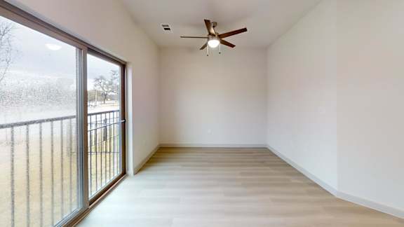 A room with a ceiling fan and sliding glass doors at Bridge at Saffron Apartments, Austin, TX