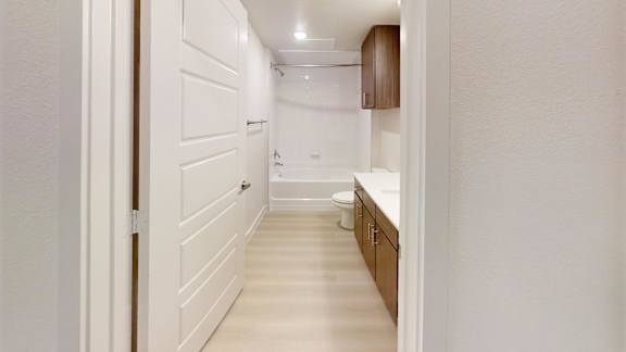 A white hallway with a toilet and sink in the distance.