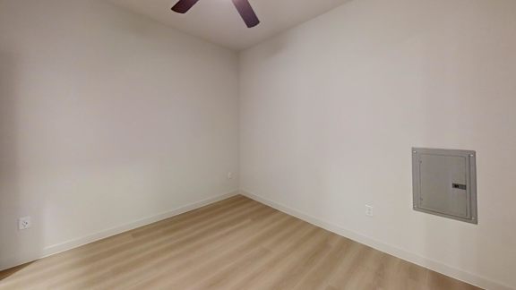 A room with a ceiling fan and a light switch on the wall.