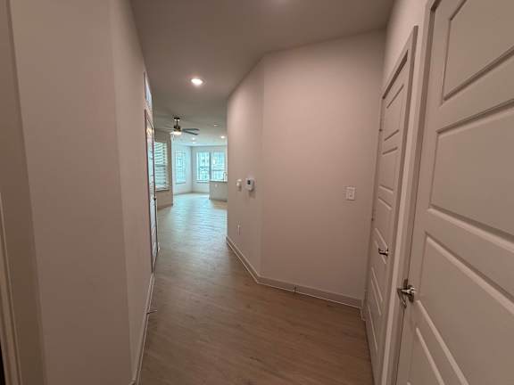 A long hallway with white walls and wood flooring.
