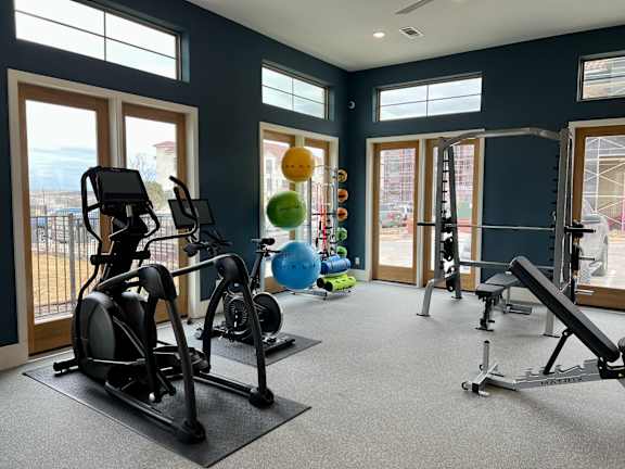 A gym with a variety of equipment including treadmills, stationary bikes, and weight machines. at Bridge at Delco Flats Apartments, Austin, 78724