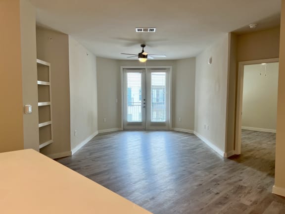 an empty living room with a ceiling fan and bookshelf