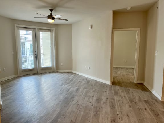 an empty living room with a ceiling fan and french doors