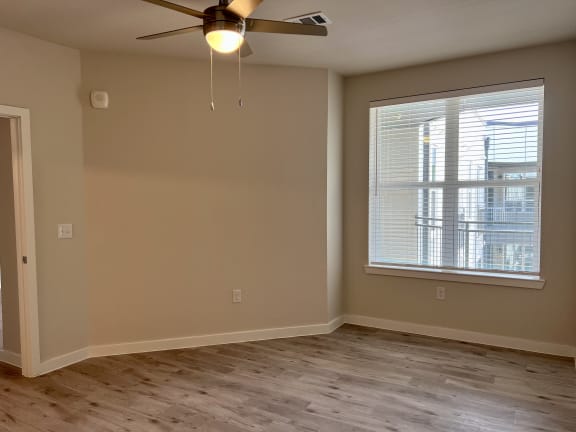 an empty room with a ceiling fan and a window