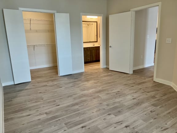 a bedroom with hardwood floors and a doorway leading to a bathroom