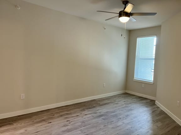 an empty room with a ceiling fan and a window