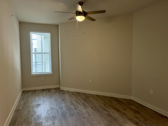 an empty room with a ceiling fan and a window
