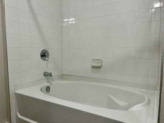 a white bathtub in a white tiled bathroom