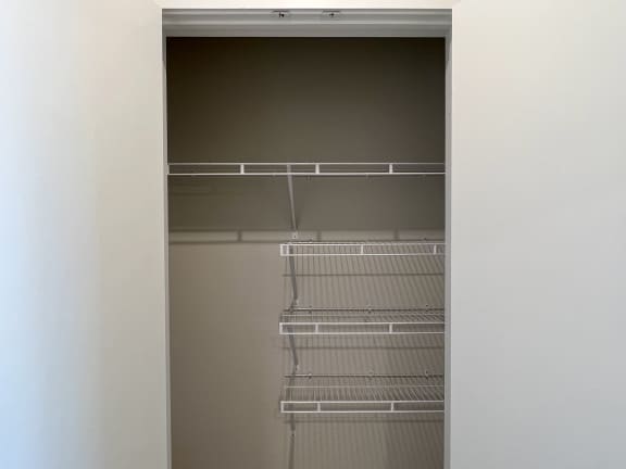 a walk in closet in a bedroom with white walls and a door that is open to a