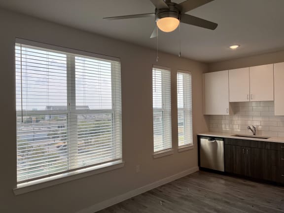 a kitchen with large windows and a ceiling fan
