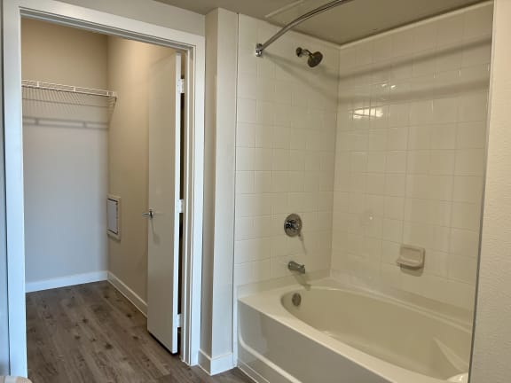 Bathroom with tiled tub shower and adjacent walk-in closet at Bridge at Windsor Park Apartments, Austin, 78723