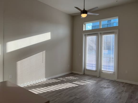 Sunlit living room with french doors and ceiling fan at Bridge at Windsor Park Apartments, Austin, Texas