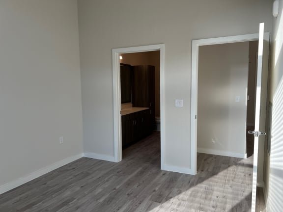 Empty bedroom with doorway to ensuite bathroom at Bridge at Windsor Park Apartments, Texas