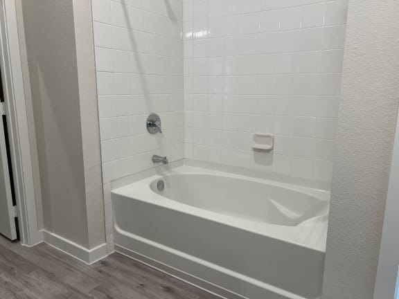 White bathtub with subway tile surround and chrome fixtures at Bridge at Windsor Park Apartments, Austin, TX