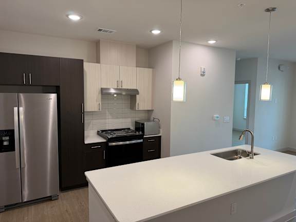 A modern kitchen with a stainless steel refrigerator and a white countertop.