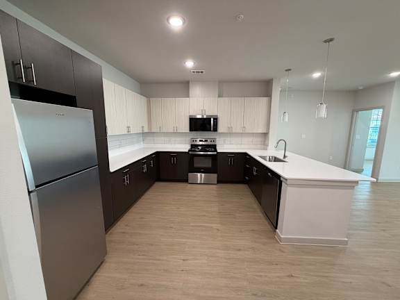 A modern kitchen with a refrigerator on the left and a sink on the right.