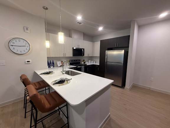 A kitchen with a white countertop and brown chairs.