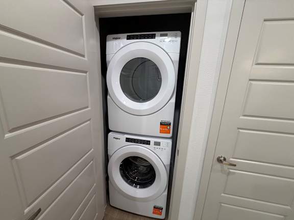 A white washing machine is in a small space between two doors.