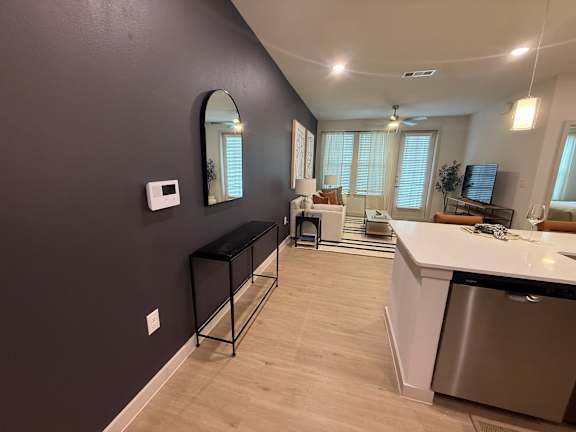 A kitchen with a stainless steel dishwasher and a black bar stool.