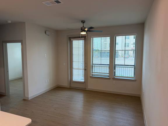 A room with a ceiling fan and sliding glass doors.