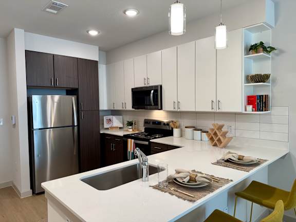 A modern kitchen with a white countertop and a stainless steel refrigerator.