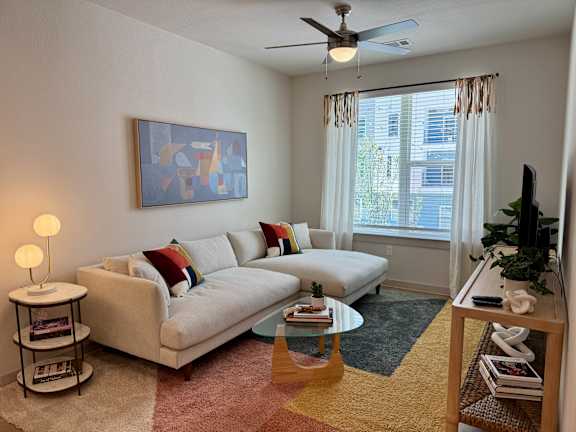 A living room with a white couch and a painting on the wall.