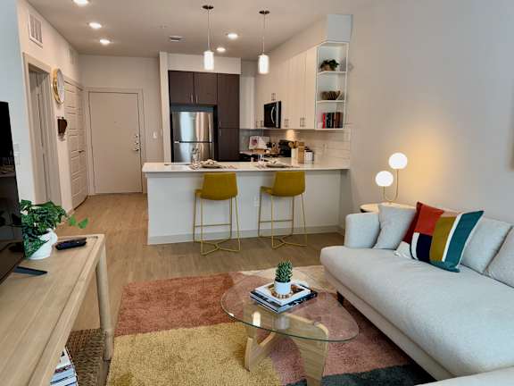 A modern living room with a white sofa, yellow chairs, and a glass coffee table.