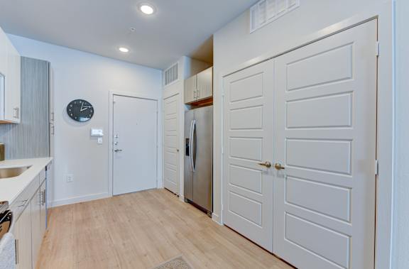 Entryway with stainless refrigerator and white paneled doors at Matador Apartments, Austin