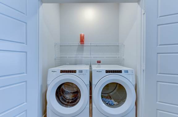 Two washing machines are in a small laundry room. at Park South Apartments, Austin