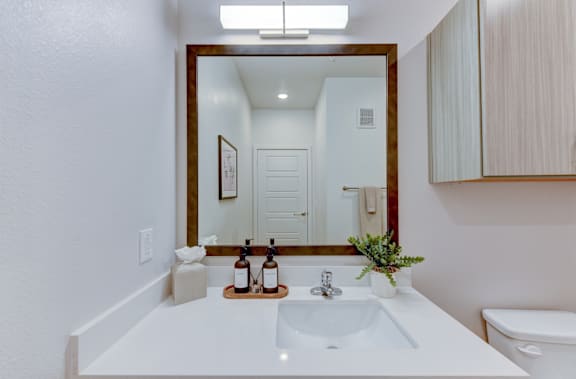 Modern bathroom vanity with wooden framed mirror at Matador Apartments, Texas
