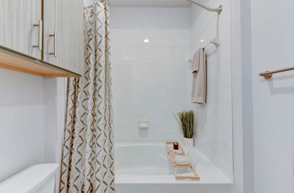 A white bathroom with a bathtub and a shower curtain. at Park South Apartments, Austin, 78748