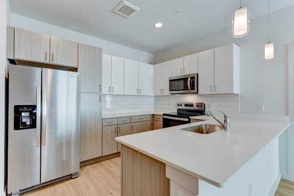 A modern kitchen with a stainless steel refrigerator and a white countertop. at Park South Apartments, Austin, Texas